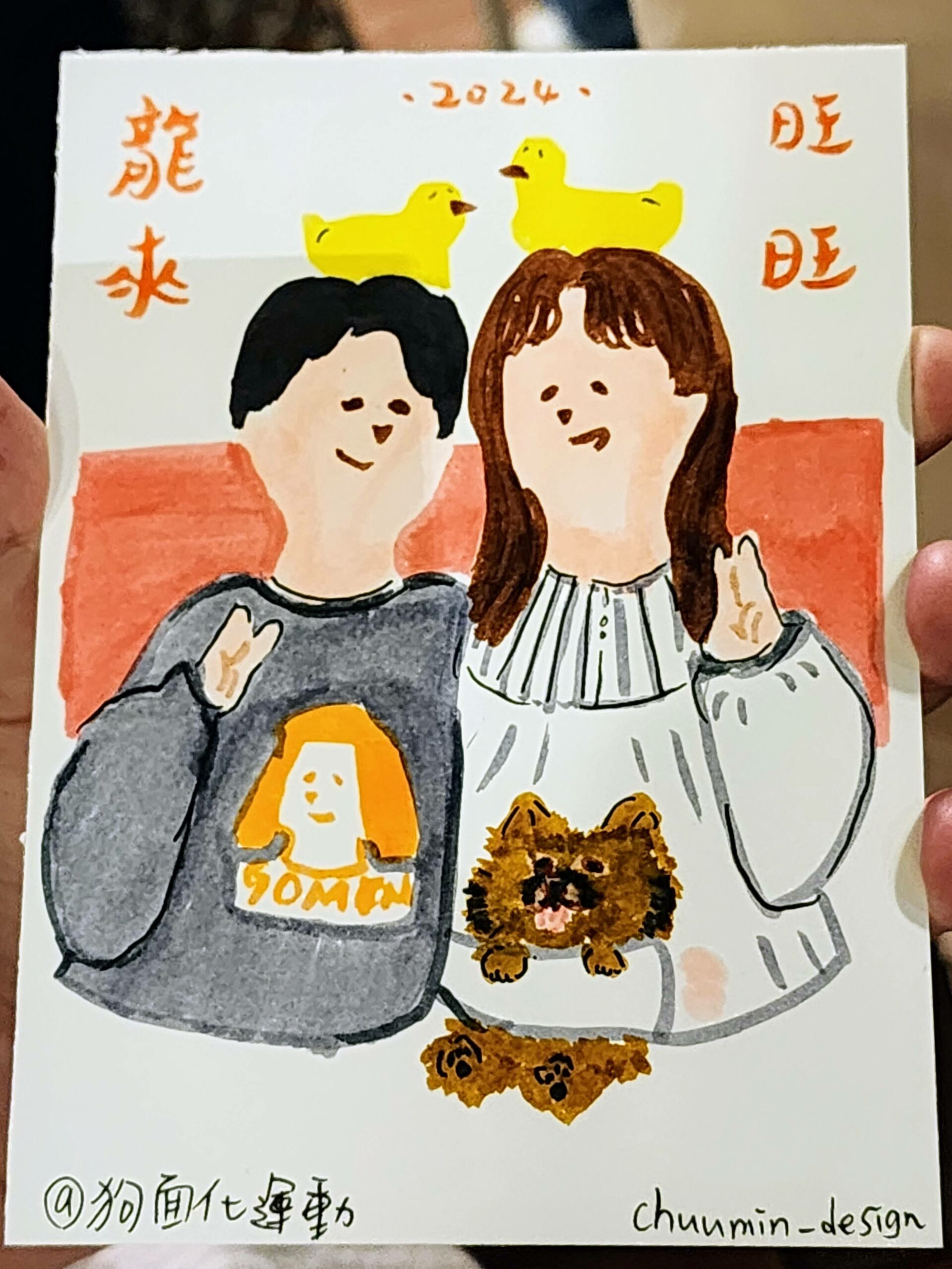 The image displays a hand-drawn illustration of two characters side by side, smiling and appearing in a cheerful pose. Both characters are wearing sweaters, with the character on the left sporting a grey one with what looks like a dog's face printed on it and the word "GOMIN," while the character on the right wears a white one with a ruffled design. Above the characters, there are two cute, yellow bird illustrations, adding a whimsical touch to the drawing. The consistent elements from the series of images include the Chinese characters "笑顔満点" at the top, meaning "Full of Smiles," and "の次の代たる者" at the bottom, translating to "The Next Generation" or "Person of the Next Era." The artwork is marked with the year "2024," which appears to be when the series was created. In the center, between the two characters, there is an additional drawing of a small brown dog, matching the print on the left character's sweater. This adds a personal touch to the illustration. The right-hand corner of the image once again features the "chuum!n- design" signature, indicating that this piece is by the same artist who created the previously shared images. This signature helps to establish a coherent style and identity across the artwork series.